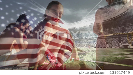 Friends gathering on sandy beach under stadium lights with red swim trunks and sports field 135617449
