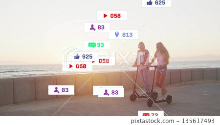 Two friends riding electric scooters along coastal path by sea wall with social icons, copy space Two friends riding electric scooters along coastal path by sea wall with social icons, copy space 135617493