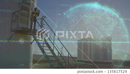 Inspecting technician using tablet on metal stairs in yard with tank, globe overlay, copy space 135617529
