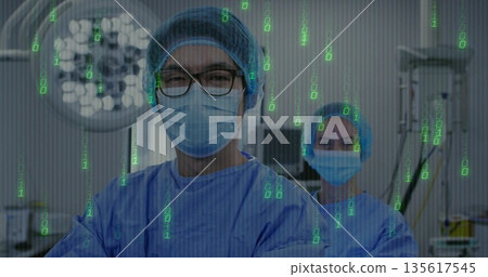 Standing male surgeon reading digital code overlay in operating room, with surgical light IV stand Standing male surgeon reading digital code overlay in operating room, with surgical light IV stand 135617545