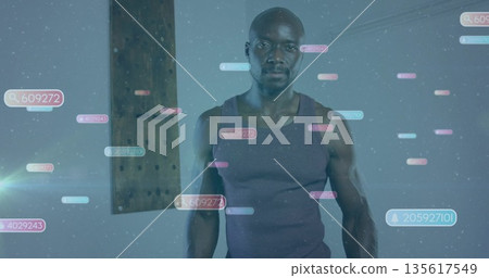 Standing athletic man wearing tank top in studio, with floating numeric overlays and wooden beam 135617549