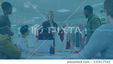 Senior designer holding up white top and guiding team in modern design studio, with garment rack Senior designer holding up white top and guiding team in modern design studio, with garment rack 135617583