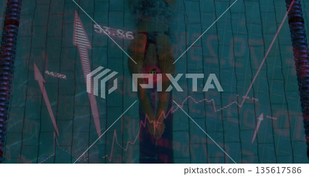 Swimmer wearing swimsuit and swim cap pushing off in competition pool, with lane ropes, graphics 135617586