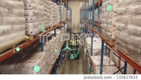 Driving forklift wearing yellow hard hat and vest through aisle, with stacked sacks and shelves 135617633
