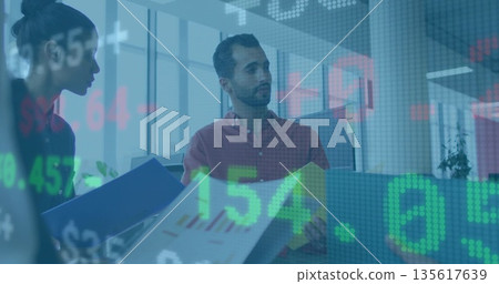 Reviewing office colleagues analyzing financial charts at office desk, with digital stock ticker Reviewing office colleagues analyzing financial charts at office desk, with digital stock ticker 135617639