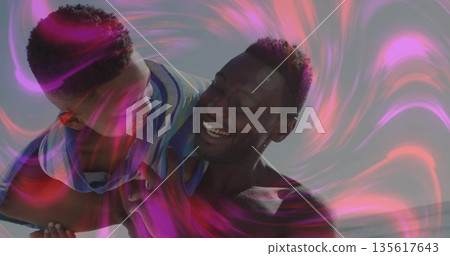 Shirtless father lifting smiling boy over shoulder on beach, with striped shirt and light patterns Shirtless father lifting smiling boy over shoulder on beach, with striped shirt and light patterns 135617643