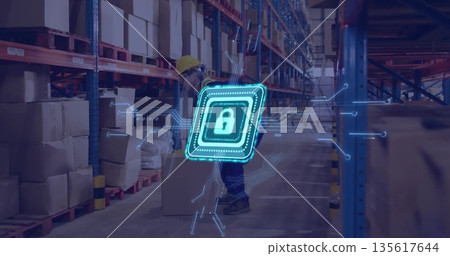 Male worker wearing hard hat lifting cardboard box in warehouse, with metal racks, padlock graphic 135617644