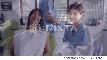 Examining patient reclining in dental chair at clinic, with dentist holding tool and suction bowl 135617652