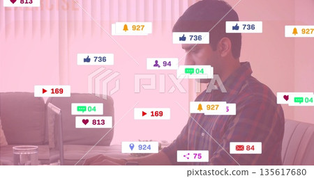 Sitting man typing on laptop in living room with social media notification icons, copy space 135617680
