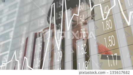 Examining businesswoman analyzing bar charts and line graph on digital display in office 135617682