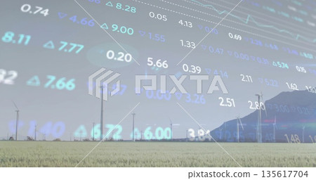 Displaying row of wind turbines rotating in grassland by mountain ridge, with stock ticker overlay 135617704