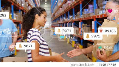 Handing female volunteer passing package to man in warehouse, with notification icons, copy space 135617746