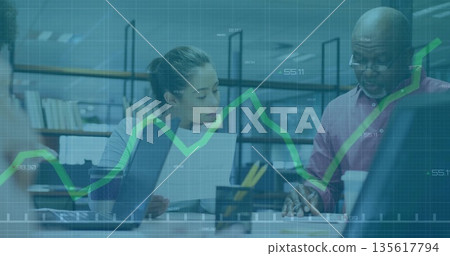 Two coworkers reviewing financial data, working on laptops in office, with documents and coffee cup Two coworkers reviewing financial data, working on laptops in office, with documents and coffee cup 135617794