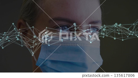 Displaying mid adult woman's face wearing surgical mask in lab, showing luminescent nodes overlay Displaying mid adult woman's face wearing surgical mask in lab, showing luminescent nodes overlay 135617806