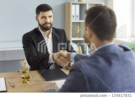 Handshake of confident lawyer and client on meeting after agreement in office 135617831