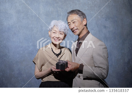 Portrait of a senior couple holding a gift Portrait of a senior couple holding a gift 135618337