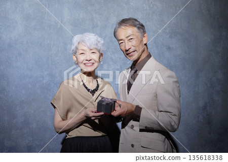 一對老年夫婦手持禮物的肖像 135618338