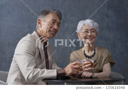 Senior couple drinking whiskey toasting black background 135618340
