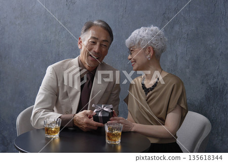 一對老年夫婦在黑色背景下喝威士忌 135618344