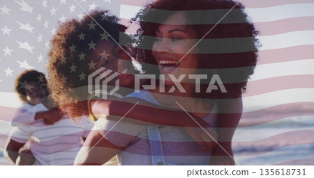 Parents giving piggyback rides on sandy beach, with American flag overlay and ocean waves Parents giving piggyback rides on sandy beach, with American flag overlay and ocean waves 135618731