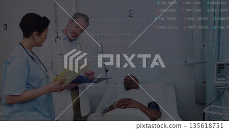 Physician in white coat and nurse in scrubs reviewing patient file in hospital, with IV stand 135618751