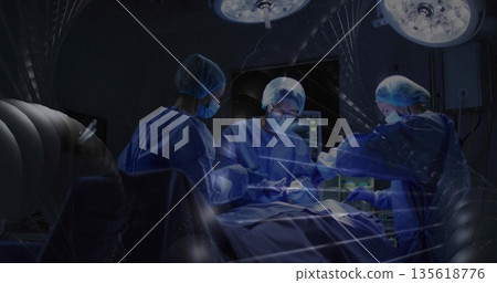 Performing surgery surgical team operating on table in hospital OR with surgical lights and monitor 135618776