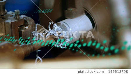 Machining cylindrical metal workpiece rotating on lathe station, with chips and green data overlay Machining cylindrical metal workpiece rotating on lathe station, with chips and green data overlay 135618798