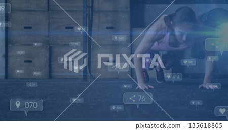 Sportswear-clad woman doing push-ups on rubber gym floor with plyo boxes, overlay icons, copy space 135618805