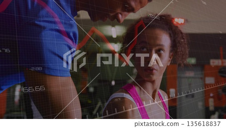 Leaning trainer in sportswear guiding client pressing weights at gym bench press with data overlay 135618837