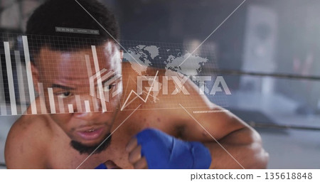 Standing shirtless boxer wearing blue wraps facing data hologram against gym ring ropes, copy space Standing shirtless boxer wearing blue wraps facing data hologram against gym ring ropes, copy space 135618848