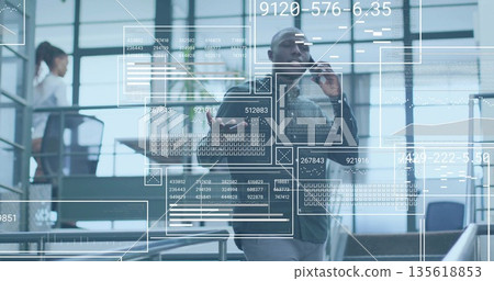 Talking African American man holding phone and tablet in office lobby, with digital overlays Talking African American man holding phone and tablet in office lobby, with digital overlays 135618853