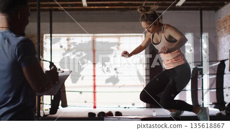 Jumping athlete clearing plyometric box in boxing ring, with trainer holding clipboard, copy space Jumping athlete clearing plyometric box in boxing ring, with trainer holding clipboard, copy space 135618867