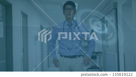 Standing doctor wearing tie in hospital corridor, with stethoscope, cart and interface overlay Standing doctor wearing tie in hospital corridor, with stethoscope, cart and interface overlay 135619122