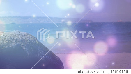 Sitting large textured boulder on sandy beach, showing coastal horizon with light orbs, copy space Sitting large textured boulder on sandy beach, showing coastal horizon with light orbs, copy space 135619156