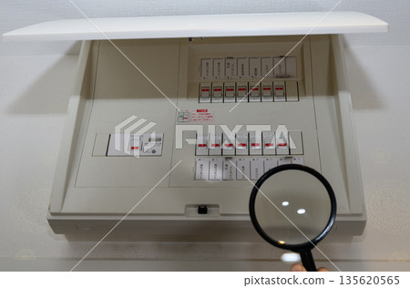 Residential distribution board and breaker viewed through a magnifying glass Residential distribution board and breaker viewed through a magnifying glass 135620565