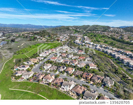Aerial view over San Juan Capistrano, California, featuring the historic mission, library, sports courts, and an Amtrak train pulling into the downtown station. 135620705