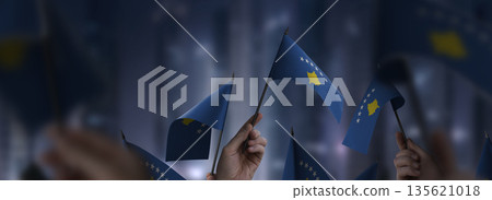Kosovo flags in their hands on a blurred urban background Kosovo flags in their hands on a blurred urban background 135621018