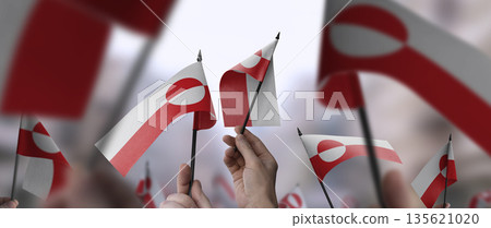 Greenland flags in their hands on a blurred urban background 135621020