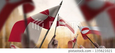 Greenland flags in their hands on a blurred urban background 135621021
