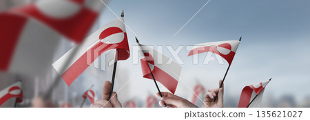 Greenland flags in their hands on a blurred urban background 135621027