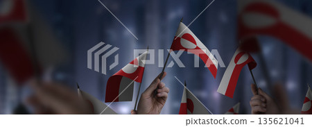 Greenland flags in their hands on a blurred urban background Greenland flags in their hands on a blurred urban background 135621041