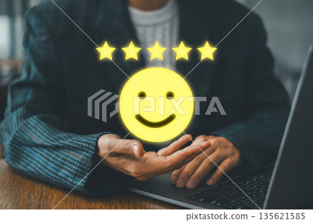A business professional presenting a glowing smiley face with five stars, representing top-notch customer service and satisfaction. 135621585