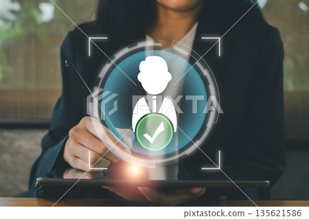 Businesswoman interacting with digital tablet, highlighting a virtual checkmark icon symbolizing successful verification or approval. 135621586