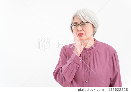 A senior woman with gray and silver hair whispering gossip, badmouthing, complaints, and nasty comments A senior woman with gray and silver hair whispering gossip, badmouthing, complaints, and nasty comments 135622228