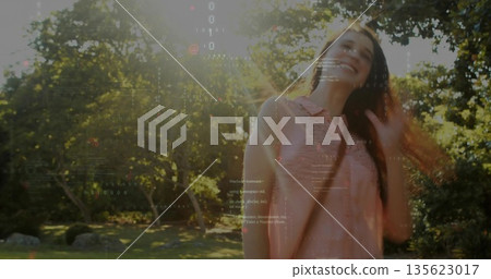 Standing adult woman wearing sleeveless pink blouse in sunlit garden, with code overlay, copy space 135623017