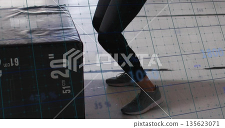 Bending legs in black leggings in gym, with labeled plyo box and grid overlay, copy space 135623071