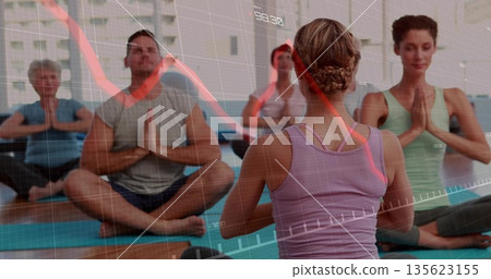 Leading instructor wearing tank top guiding students on yoga mats in studio, with financial overlay 135623155