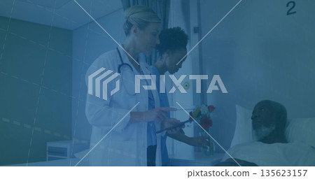 Reviewing tablet data doctor in lab coat in hospital room, nurse in blue scrubs arranging flowers Reviewing tablet data doctor in lab coat in hospital room, nurse in blue scrubs arranging flowers 135623157
