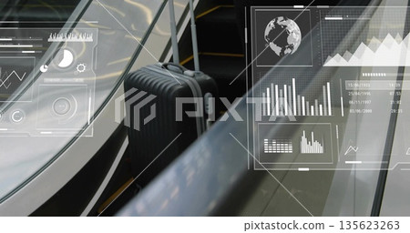 Standing black suitcase on escalator steps in terminal, showing glass handrail digital overlays 135623263
