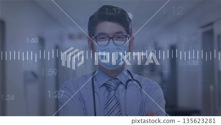 Standing male doctor monitoring waveform data in hospital corridor, wearing stethoscope and mask Standing male doctor monitoring waveform data in hospital corridor, wearing stethoscope and mask 135623281